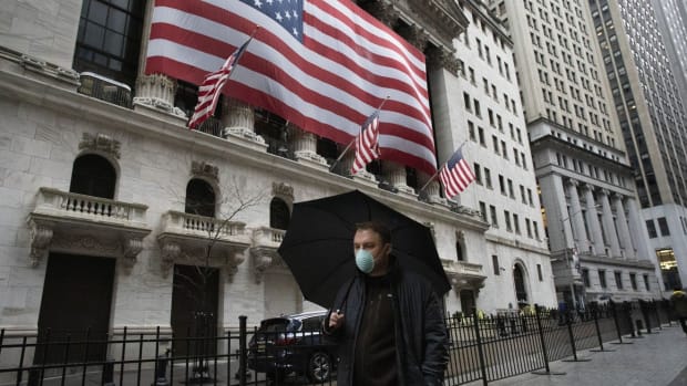 A man wearing a mask walks by the New York Stock Exchange, on Tuesday. Photo: AP Photo