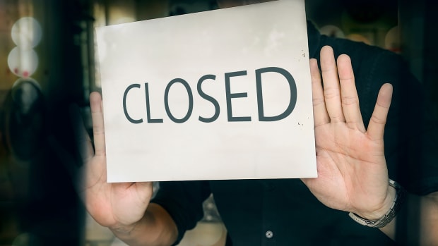 A person places a closed sign on a window. Small Businesses Coronavirus Lead