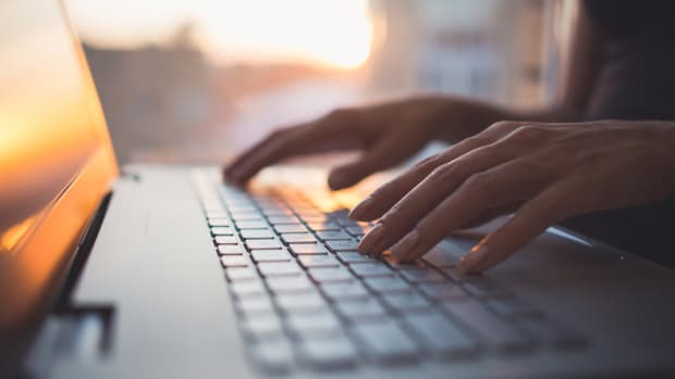 A person's fingers are seen typing on the keyboard of a computer. -lead