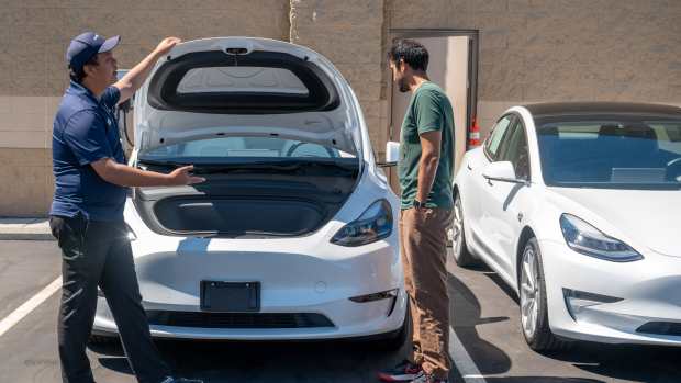 A CarMax salesman shows a used Tesla Model Y electric vehicle (EV) to a customer at a dealership in Fremont, California, US, on Monday, Aug. 19, 2024. Retail sales of used EVs jumped 70% in the first half of the year, according to market researcher Cox Automotive. Photographer: Amy Osborne/Bloomberg via Getty Images