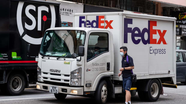 HONG KONG, CHINA - 2021/04/06: A worker of the American FedEx Express delivery is seen getting in the truck as Chinese multinational delivery services and logistics company SF Express trucks are stationed in the street in Hong Kong. (Photo by Budrul Chukrut/SOPA Images/LightRocket via Getty Images)