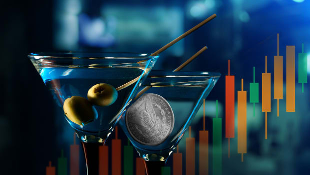 Digital image of two martini glasses, one containing alcohol and olives and the other containing a coin, on a blurred background overlaid with a candlestick-style stock chart moving in an upward direction