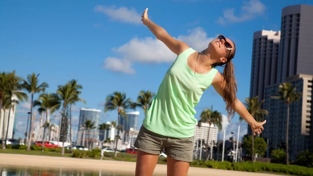 A woman is seen enjoying the sun in front of Waikiki Beach. -lead