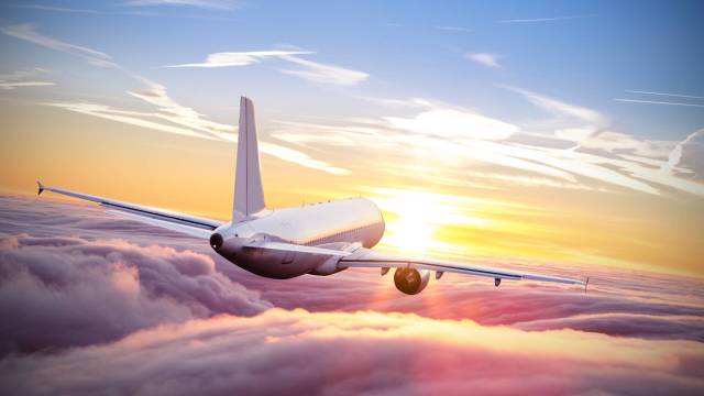 An unidentified airplane is seen flying above the clouds at sunset. -lead