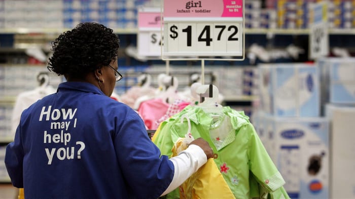 A Walmart employee hangs clothes in a store. Lead.