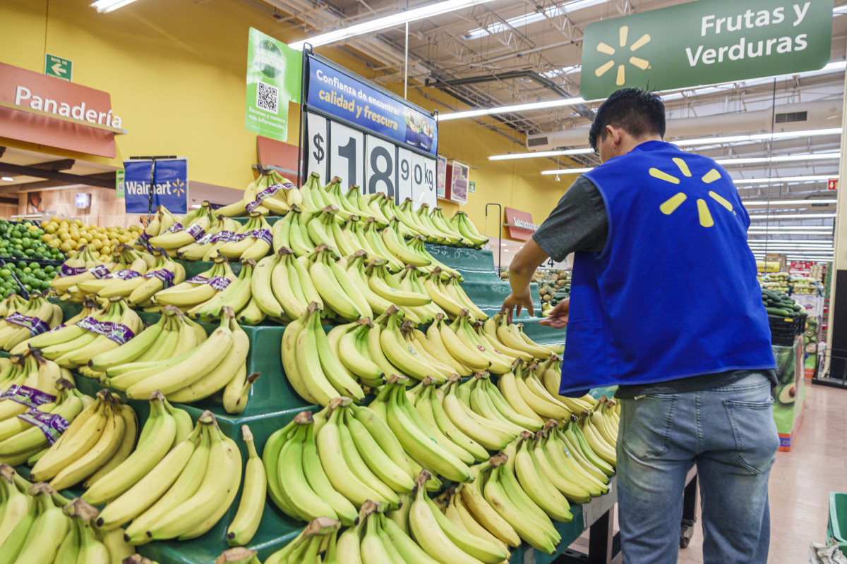 A Walmart employee restocking bananas.