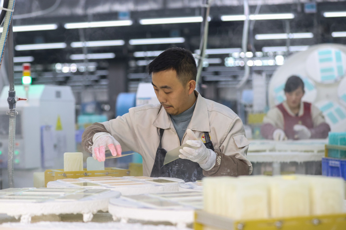 ZUNYI, CHINA - MARCH 06: An employee works on the production line of glass covers for mobile phone brands, such as Samsung, Huawei and Xiaomi, at a factory on March 6, 2023 in Zunyi, Guizhou Province of China. (Photo by Qu Honglun/China News Service/VCG via Getty Images)